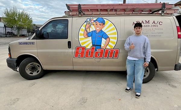 Beige service van with “Adam” logo parked outdoors beside a person in a gray shirt and jeans