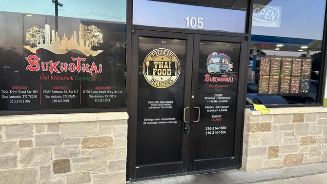 Storefront with black double doors and windows, featuring a red sign and stone lower facade, building number 105.