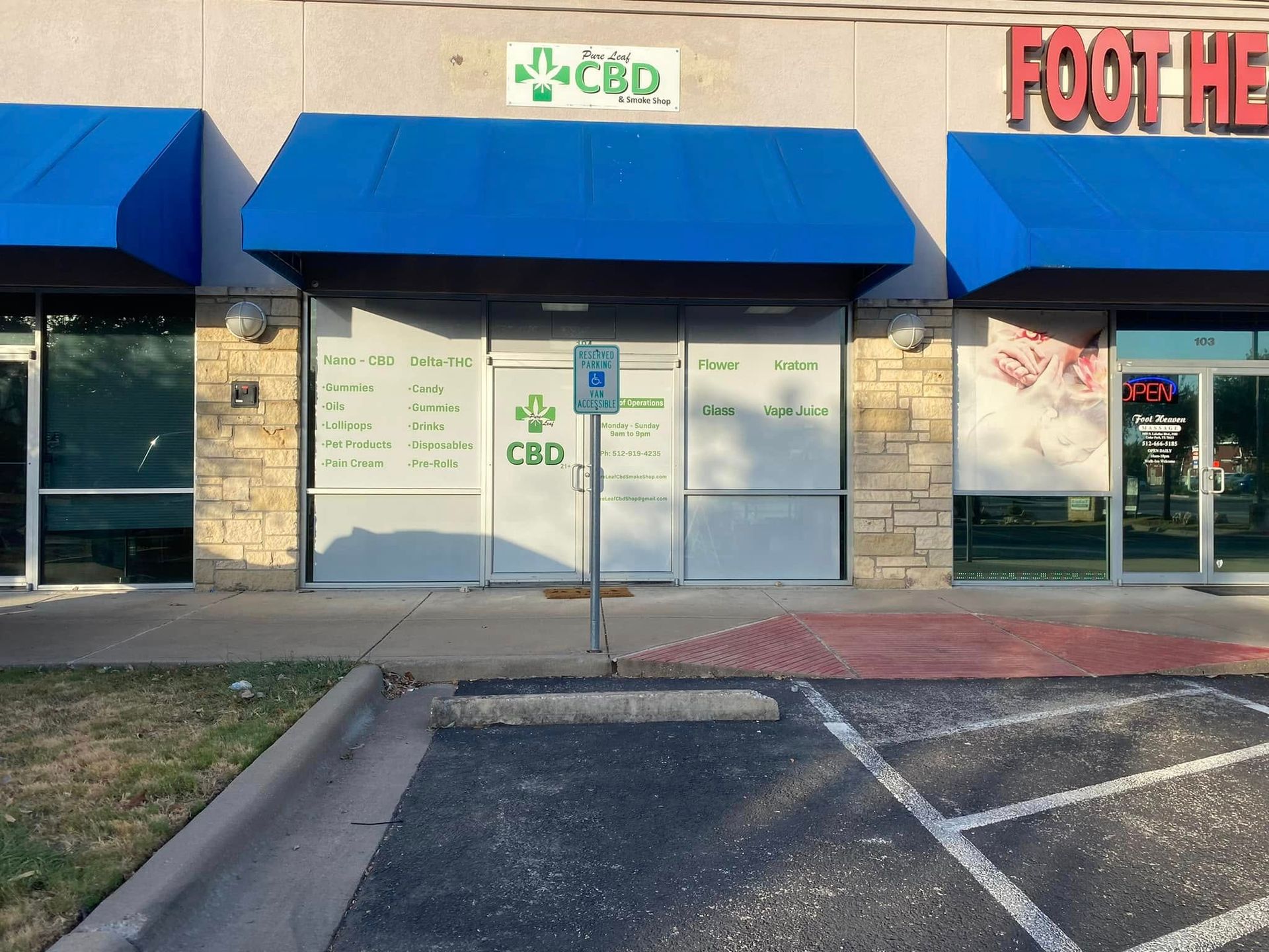 Strip-mall storefront with blue awnings and a CBD shop sign, viewed from the parking lot.