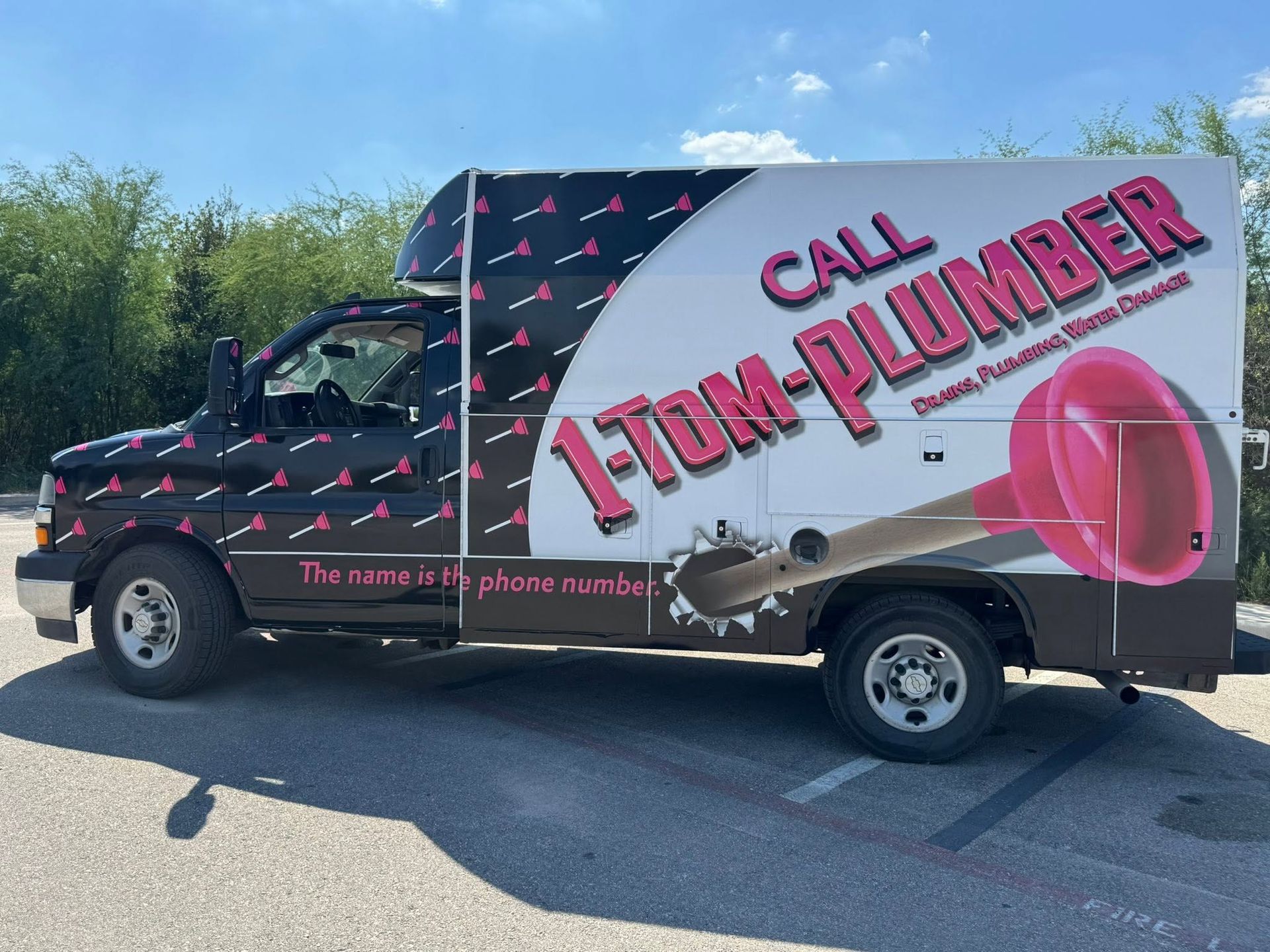 Plumbing service truck with large “AZD-PLUMBER” and “CALL” ads parked outdoors.