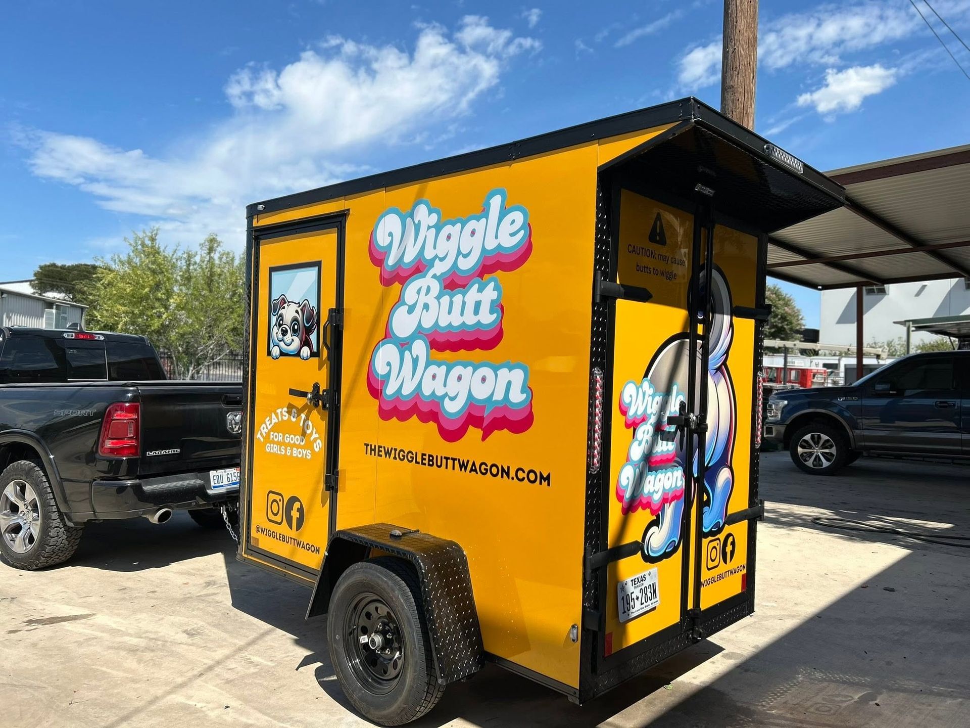 Yellow “Wiggle But Wagon” food trailer parked outdoors on a sunny day