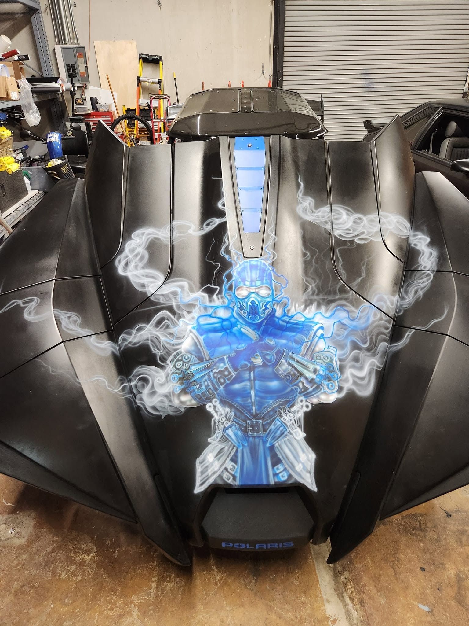 Black sports car with a blue lightning decal in a garage, front view
