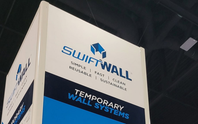 White booth display with SWIFTWALL logo and “Temporary Wall” text at an indoor trade show.