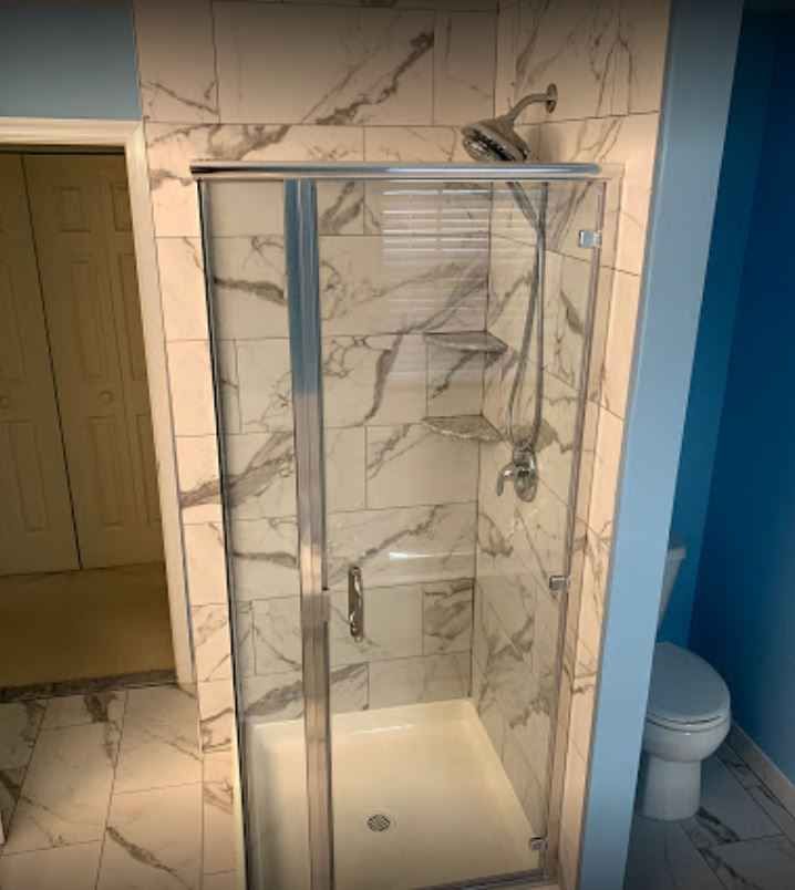 Modern bathroom with a glass shower enclosure and white marble-pattern tile walls