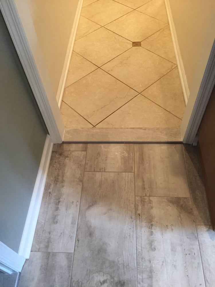 Hallway with wood-look flooring leading to a tiled entryway and doorway threshold