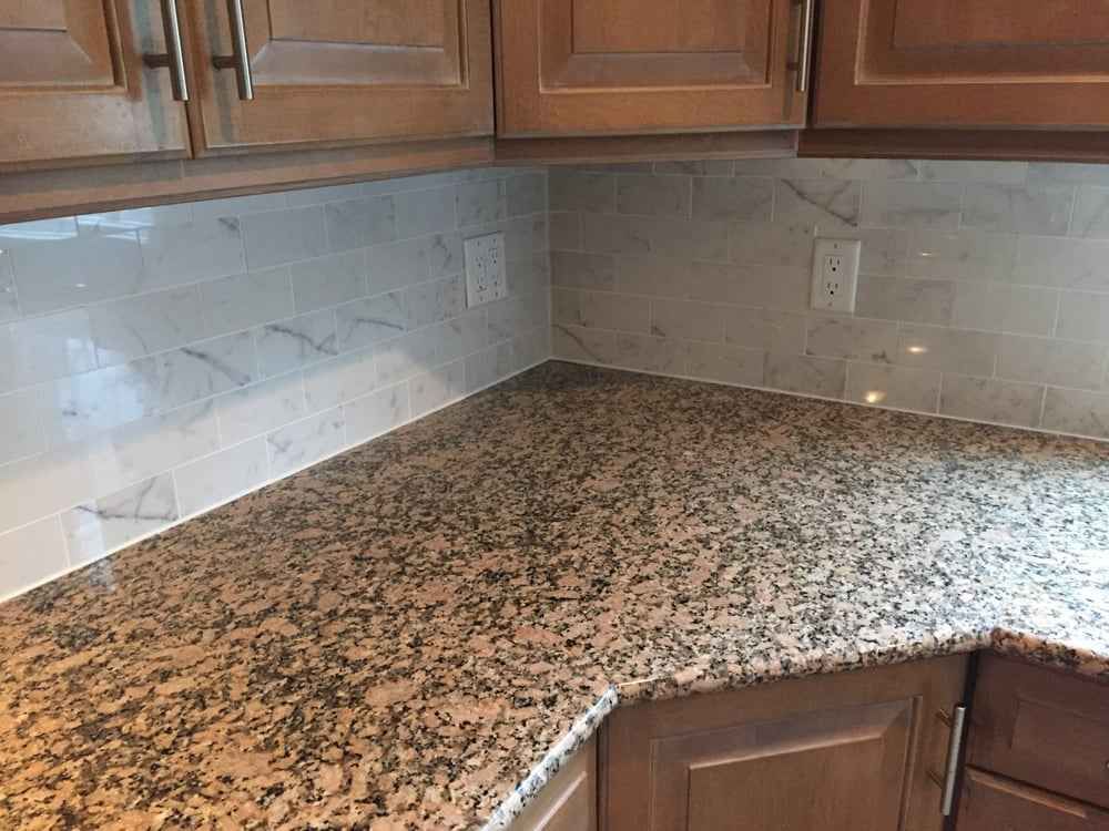 Kitchen corner with speckled granite countertop, white tile backsplash, and dark wood cabinets