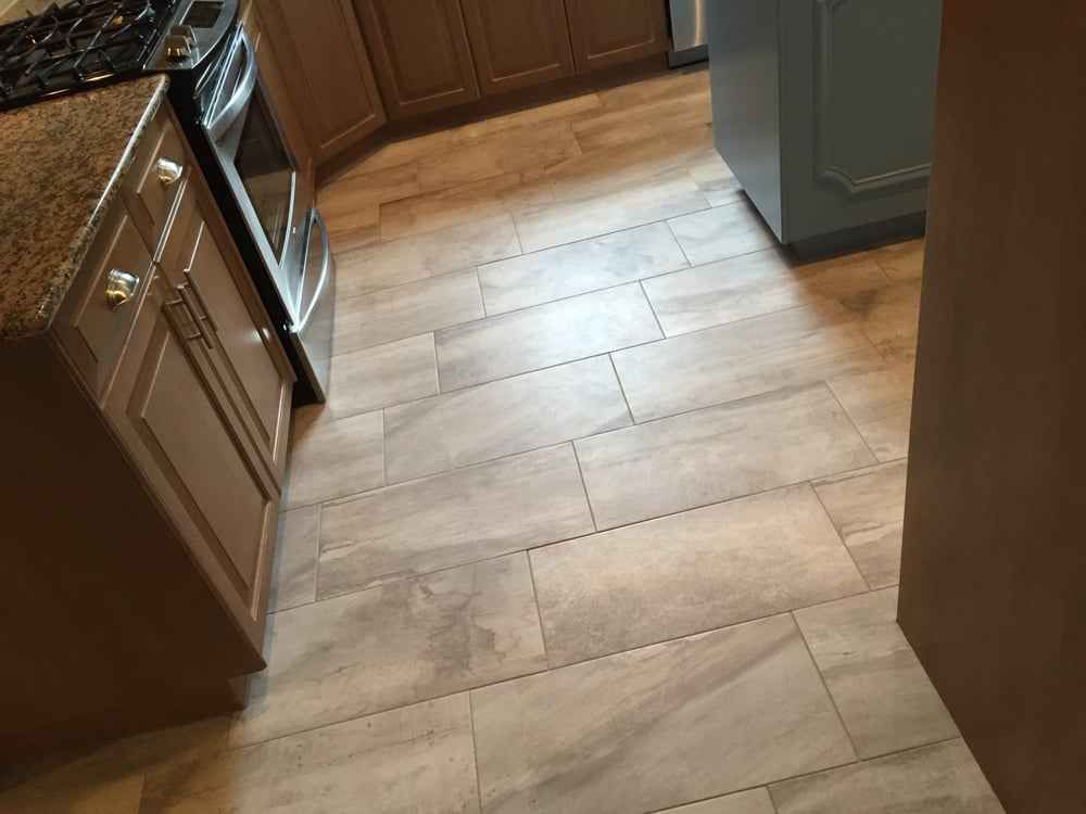 Kitchen with light wood tile floor, dark cabinets, and a stainless steel oven.