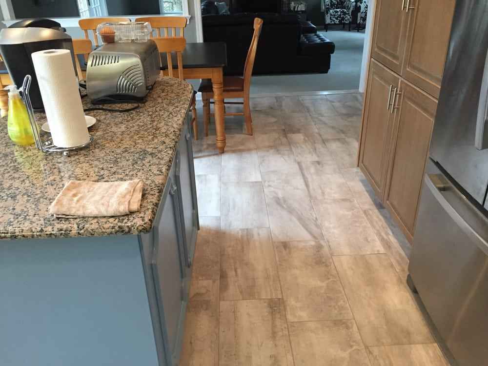 Kitchen with granite counter, stainless fridge, blue cabinets, and wood-look floor leading to dining area