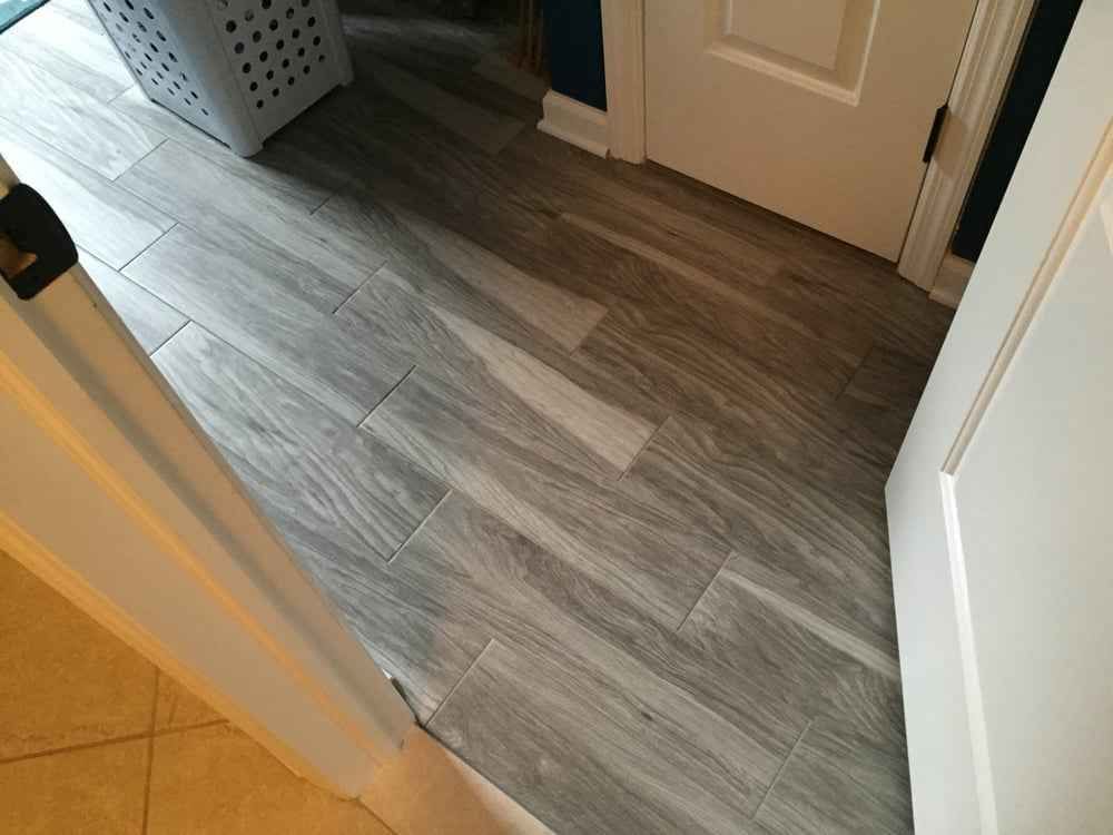 Hallway with gray wood-look flooring, white doors, and a glimpse of tan tile at left