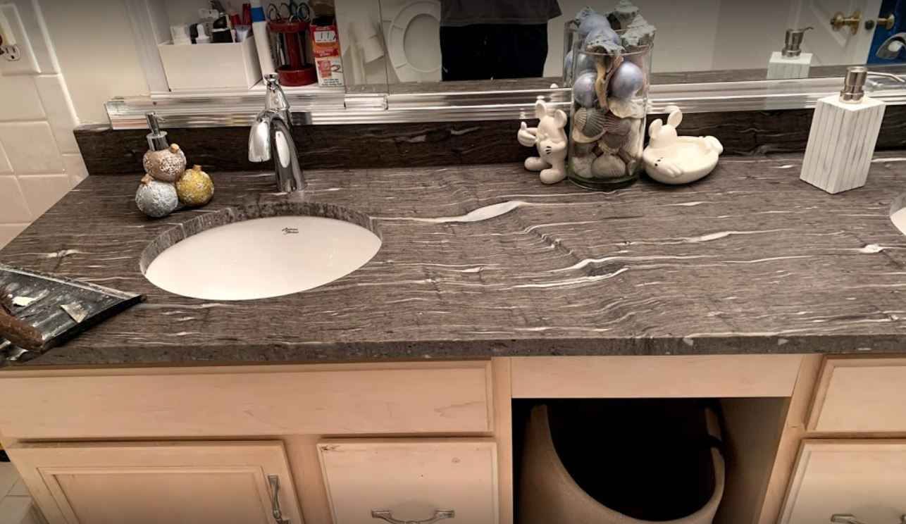 Bathroom vanity with marble countertop, white sink, and decorative figurines on the counter