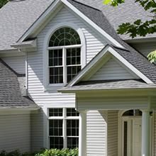 White house exterior with arched window and gray shingled roof