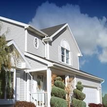 White house exterior with gabled roof and manicured shrubs under a blue sky