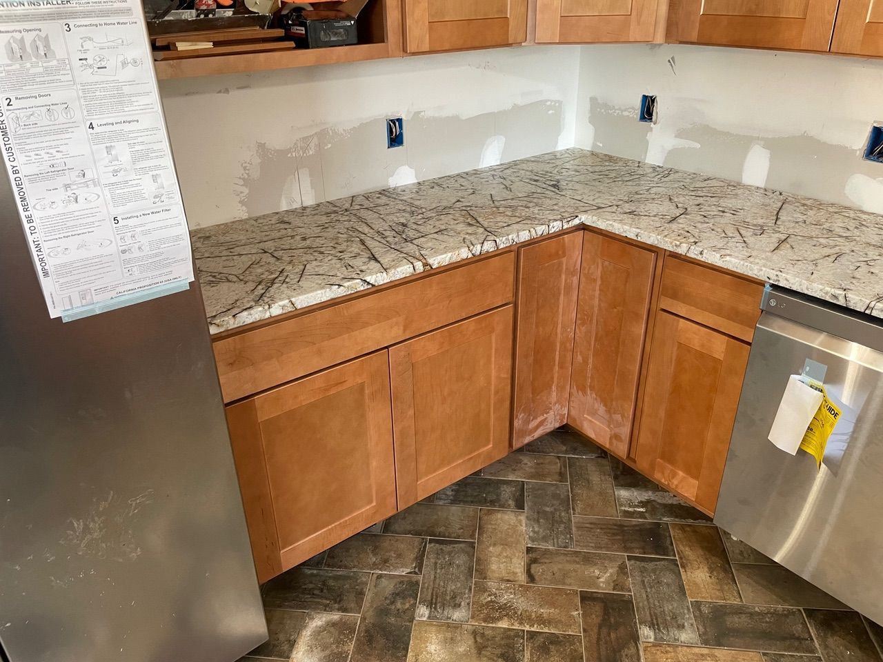 Kitchen corner with granite countertops, wooden cabinets, stainless steel appliances, and tiled floor