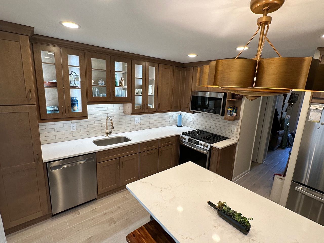 Modern kitchen with wood cabinets, stainless appliances, white countertops, and a center island with pendant lights.