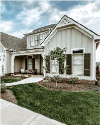 Suburban house with beige siding, covered porch, and landscaped front yard under a cloudy sky