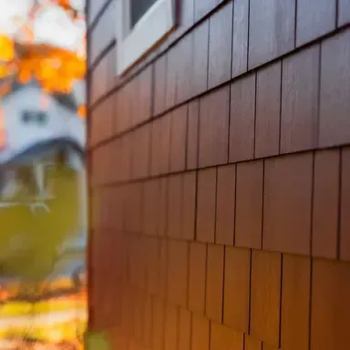 Blurred street scene with an orange autumn tree and a brown tiled wall in the foreground
