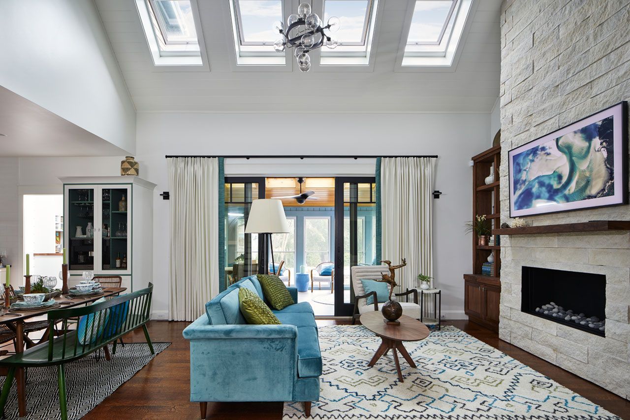 Bright living room with skylights, blue sofa, fireplace, and sliding glass doors to a patio
