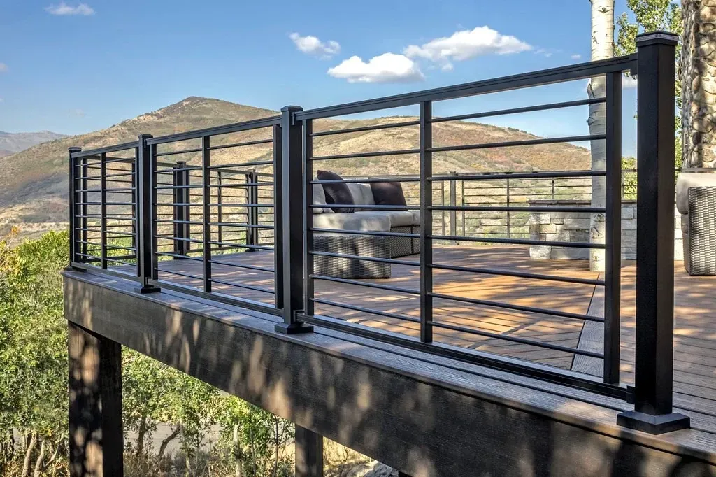 Outdoor deck with black cable railing, chair, and mountain landscape in the background