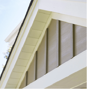 Close-up of a house roof eave with white trim and beige siding panels