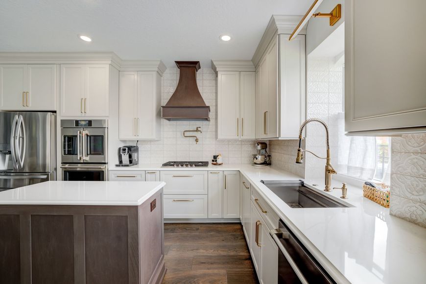 Bright modern kitchen with white cabinets, stainless appliances, island, and large window over sink
