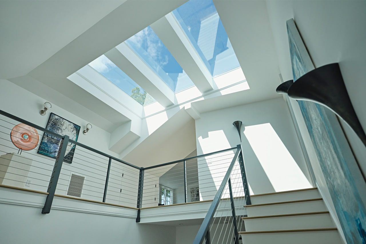 Modern stairwell with skylights, white walls, and black metal railing in a bright interior