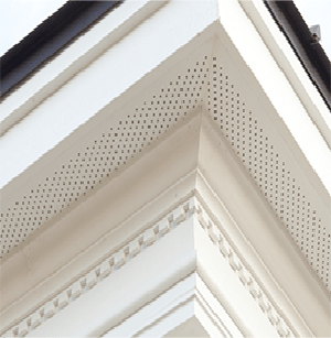 Close-up of a white house roof eave with decorative trim and perforated soffit details