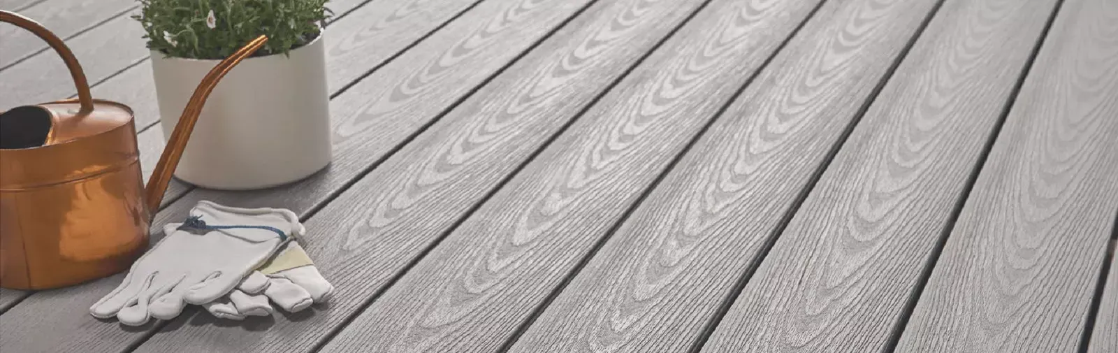 Potted plants and white flowers on a gray wooden deck