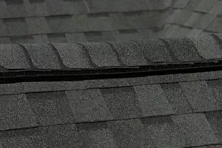 Close-up of dark gray roof shingles with a raised ridge and layered rows.