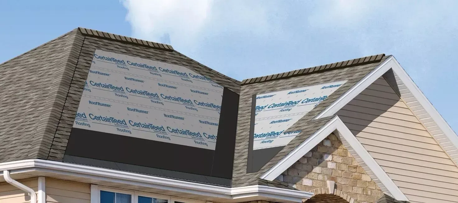 House roof with exposed sheathing panels and unfinished siding under a blue sky
