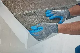 Gloved hands smoothing a gray textured surface on a white ledge