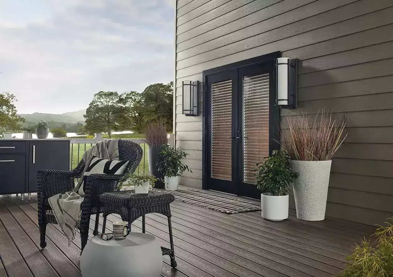 Modern outdoor patio with dark furniture, potted plants, and a house exterior with sliding doors.