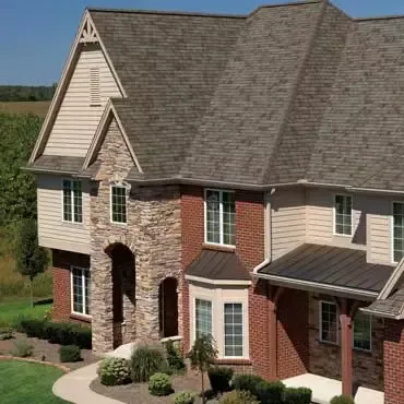 Two-story suburban house with brick, stone, and beige siding under a gray shingle roof