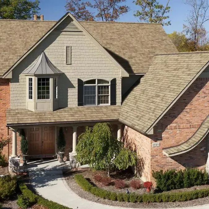 Suburban house with brick and shingle exterior, front porch, bay window, and curved driveway.