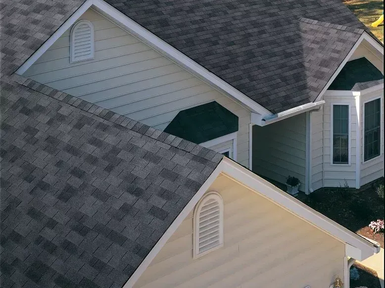 Overlapping gray and beige house roofs with dormer windows and shingles