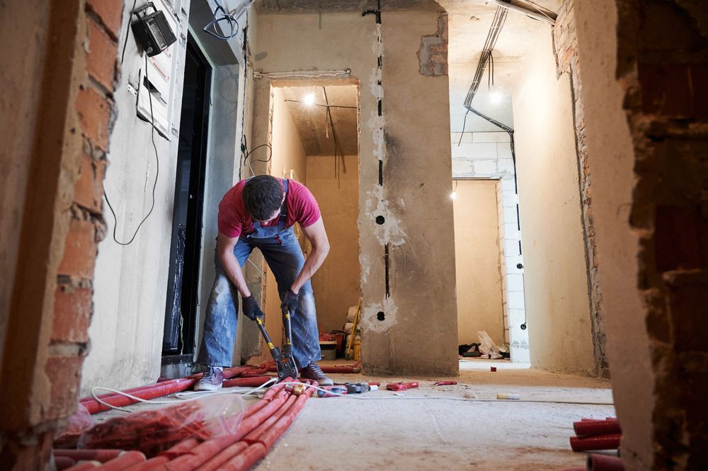 A Man Is Working on The Floor of A Building — Sydney Underfloor Heating in Nowra, NSW
