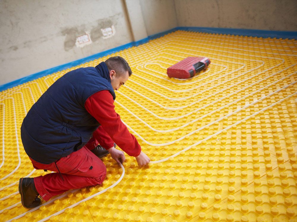 Worker Installing Underfloor Heating And Cooling In Modern Home — Sydney Underfloor Heating in Woonona, NSW