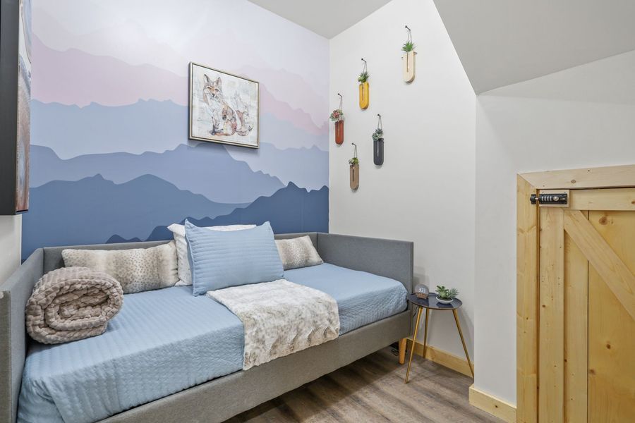 Bedroom with a daybed, mountain mural, and decorative wall hangings.