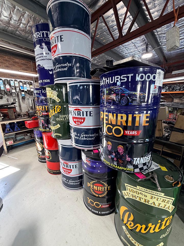 Stacked Penrite oil drums in a warehouse with exposed beams.