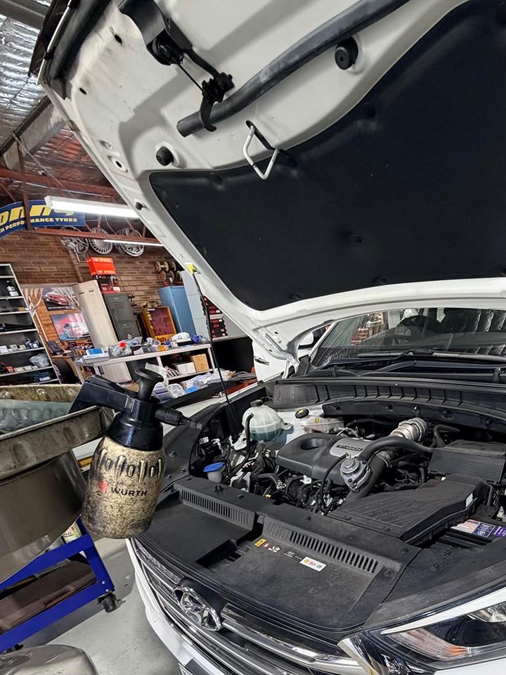 Open car hood in auto shop with engine exposed and tools nearby