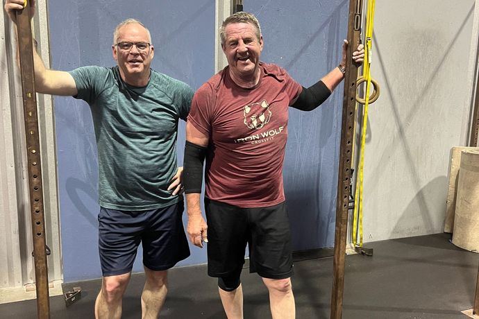 Two men are standing next to each other in a gym.
