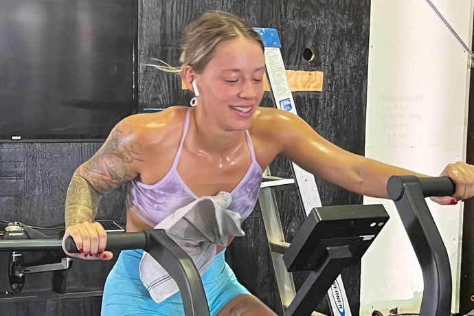 A woman is riding an exercise bike in a gym.