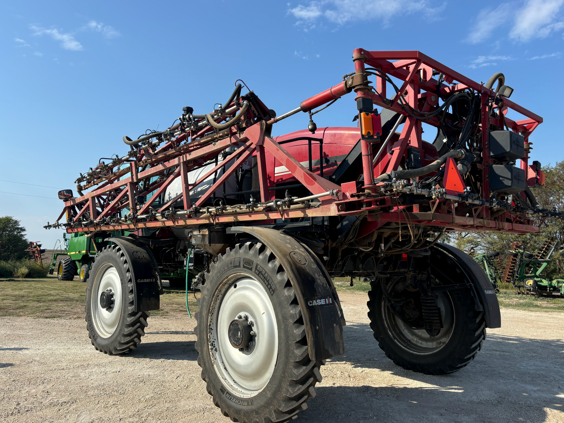 A red sprayer is parked on a dirt road.