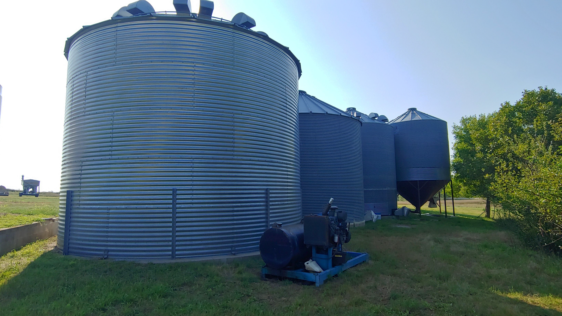 A row of silos are sitting on top of a lush green field.