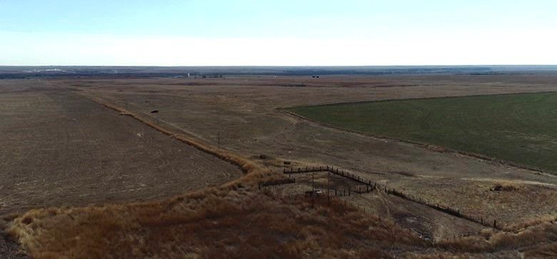 An aerial view of a field with a fence in the middle of it.