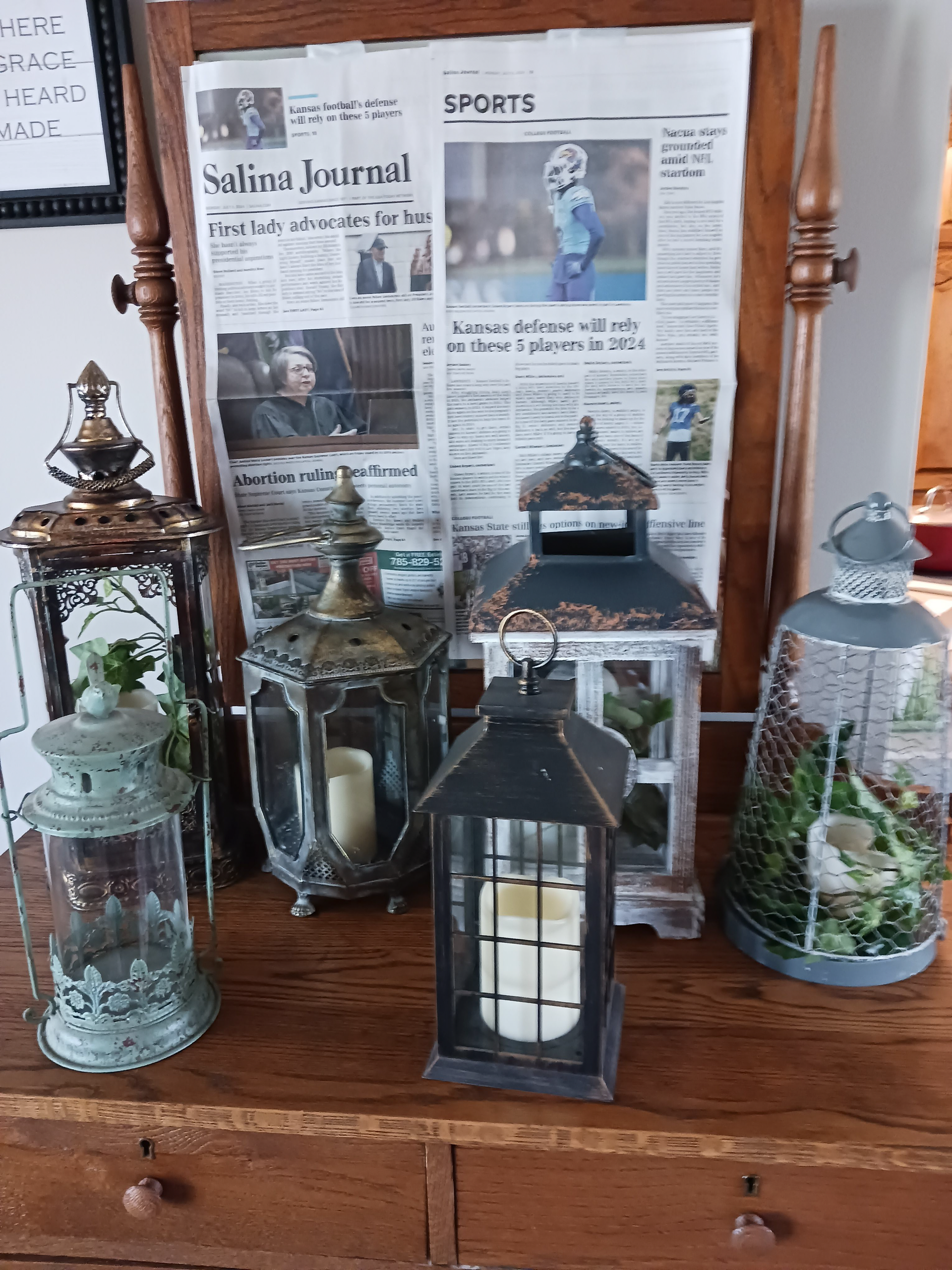 A dresser with lanterns and a newspaper on it.