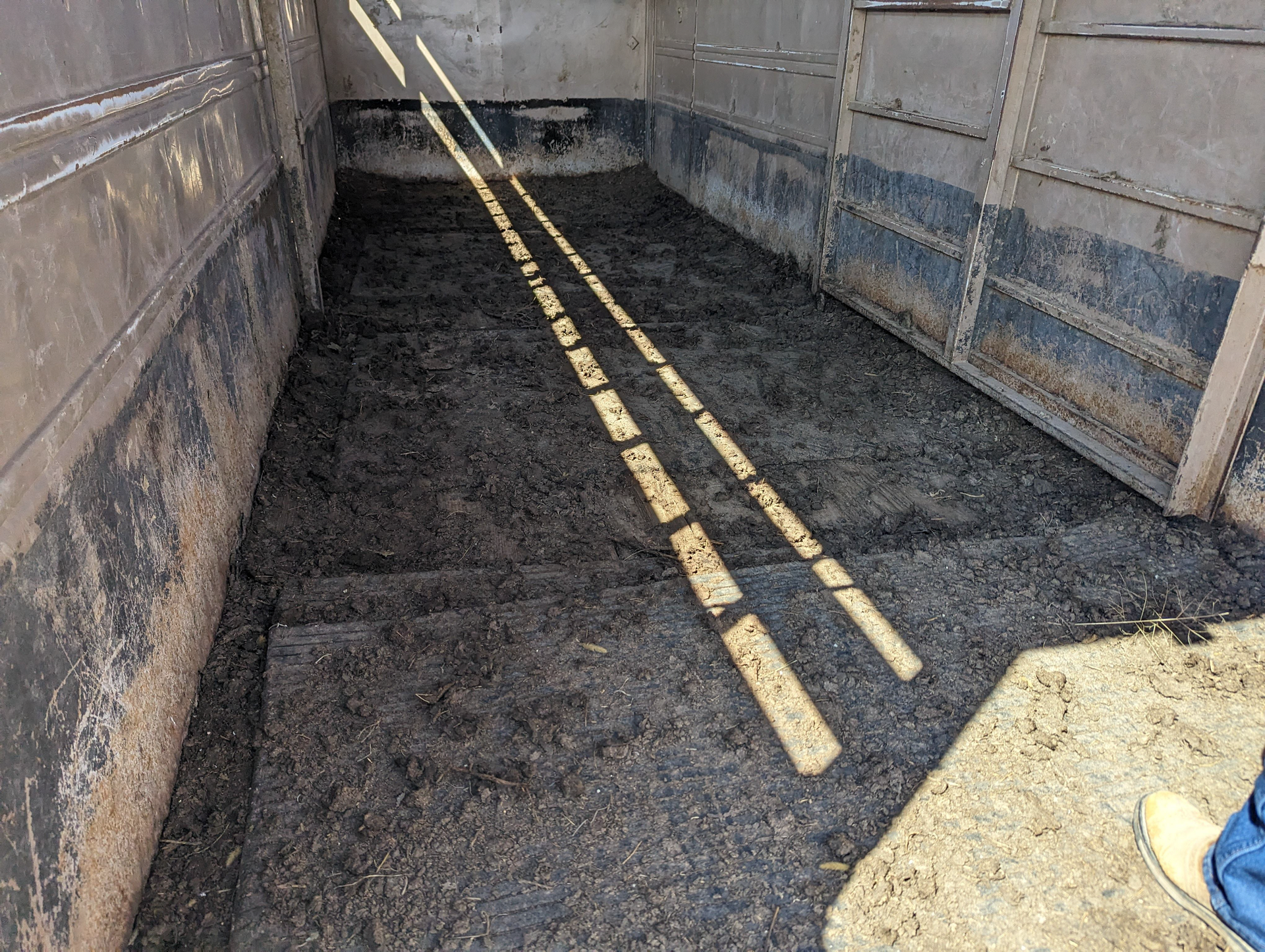 A person is standing in a dark room with a lot of dirt on the floor.