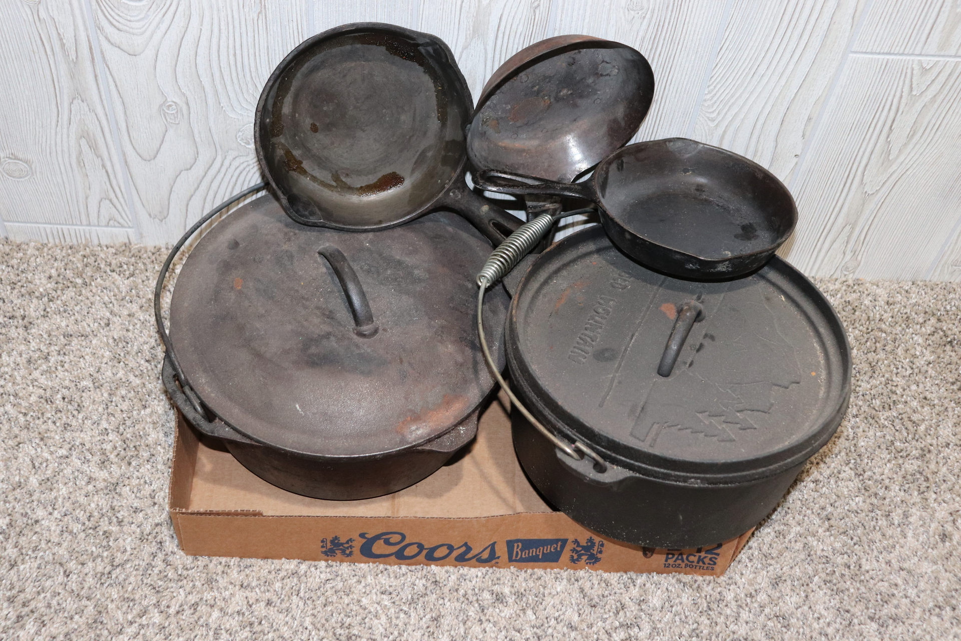 Several pots and pans are stacked on top of a box that says coors