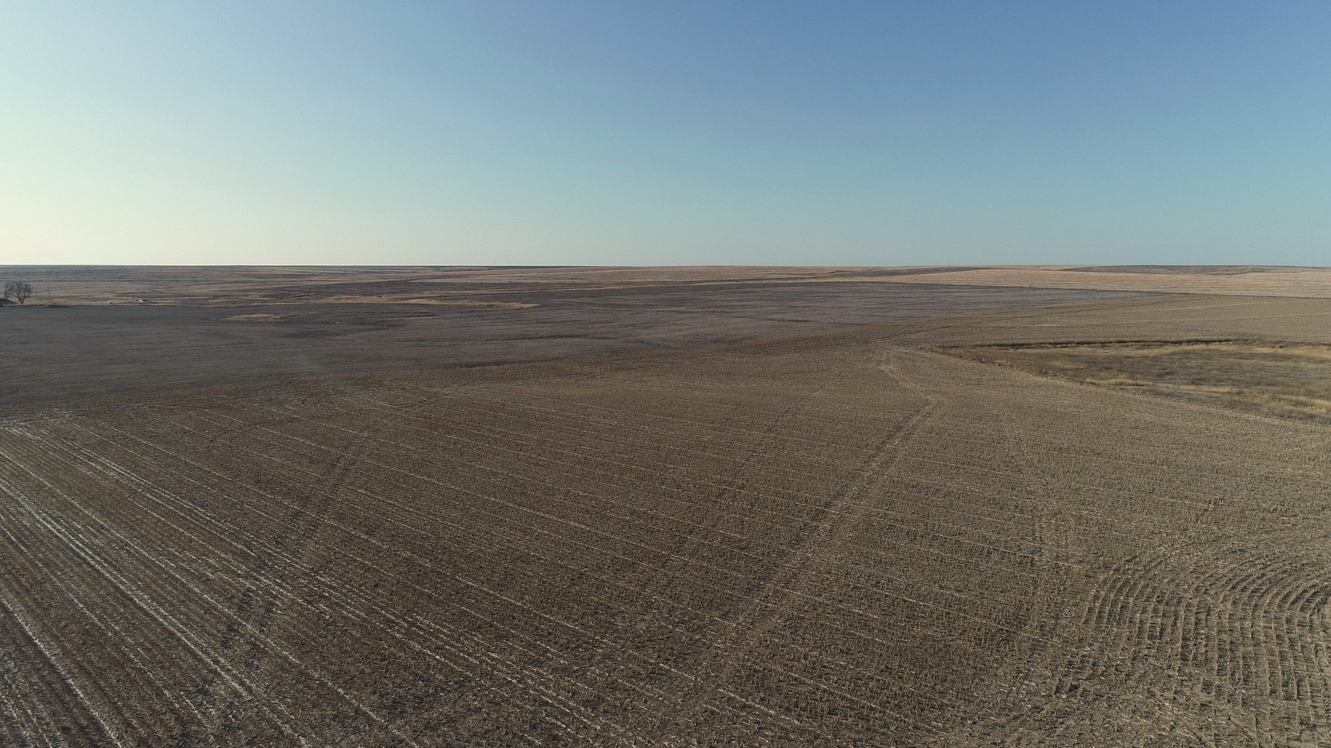 An aerial view of a large empty field with a blue sky in the background.