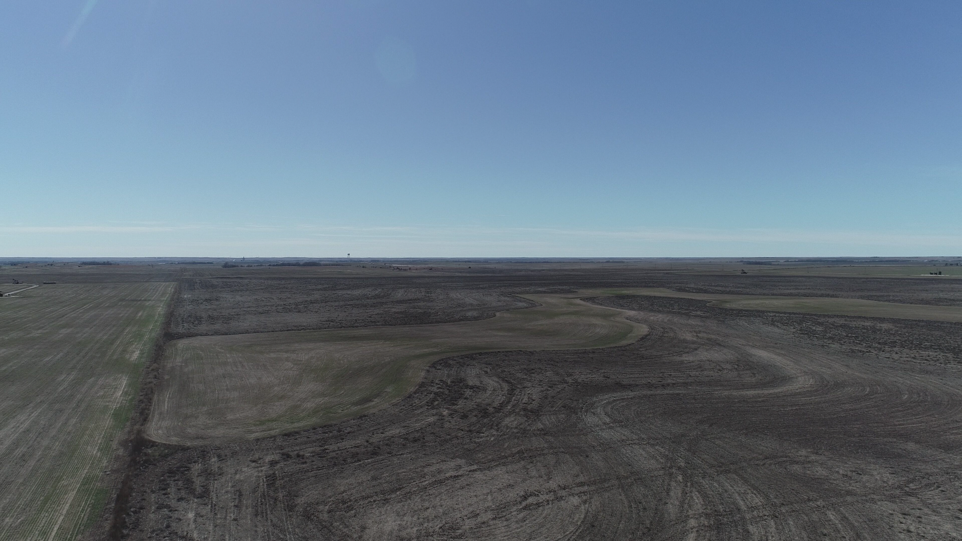 An aerial view of a dry grassy field with a blue sky in the background.