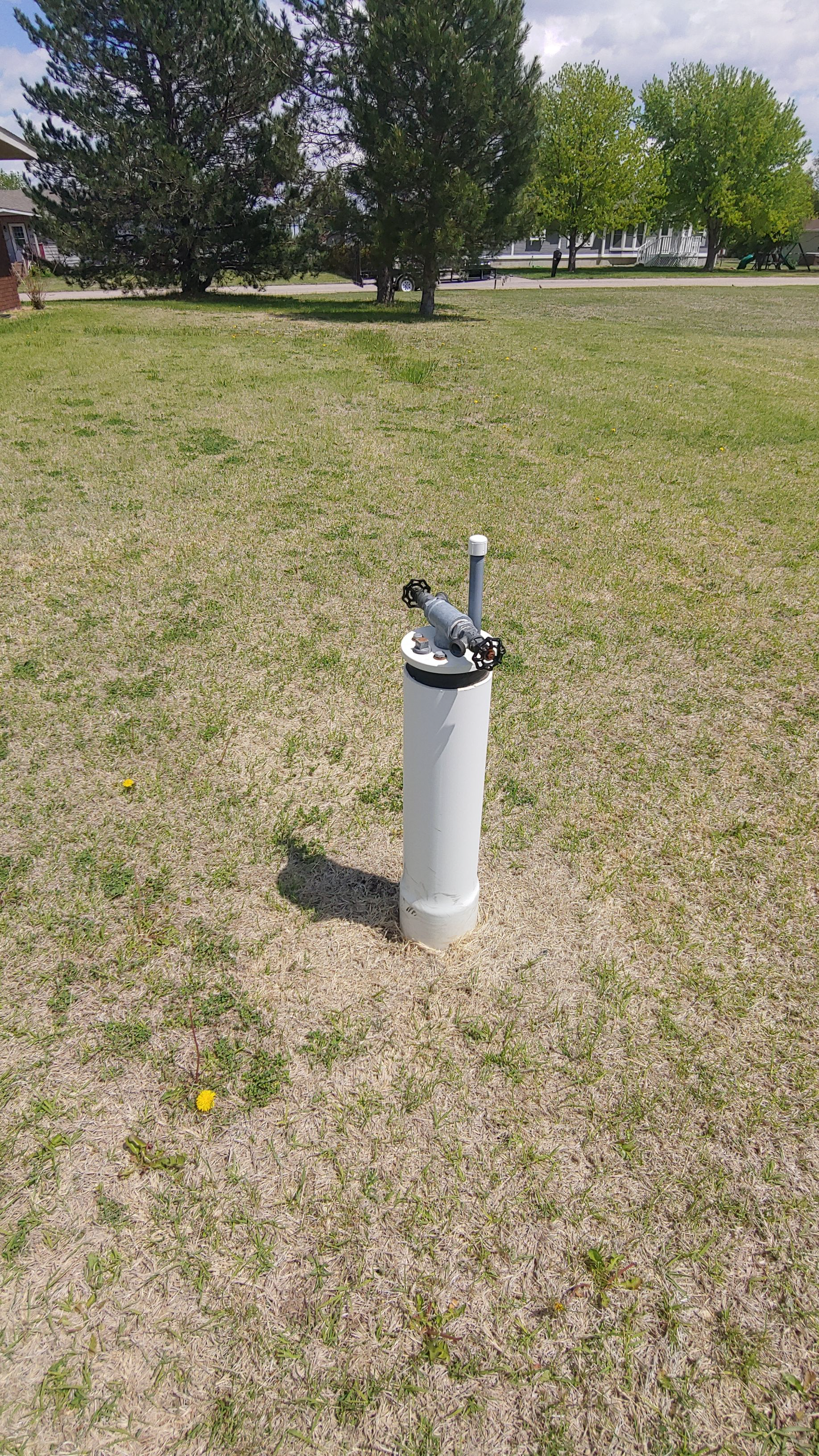 A white pipe is sitting in the middle of a grassy field.